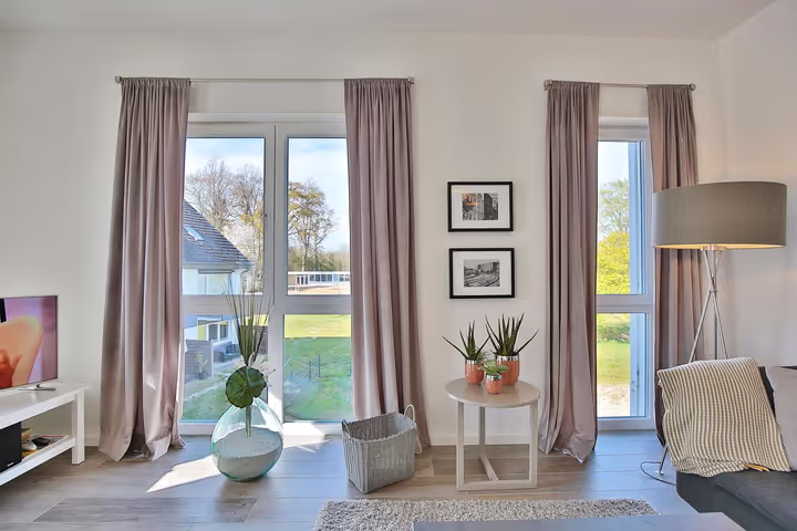 Wohnbereich mit bodentiefen Fenstern und Zugang zum Balkon