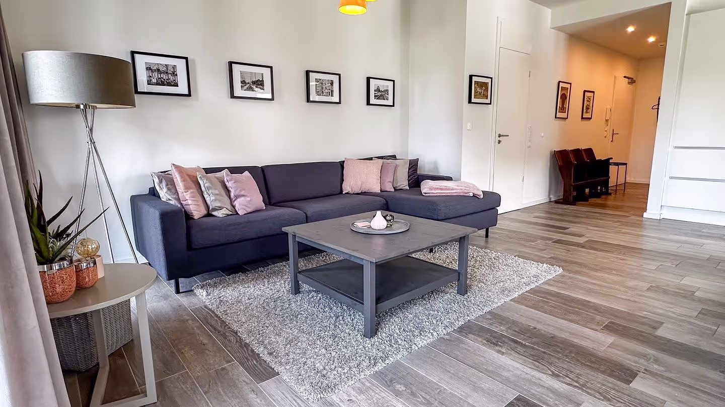 Heller Wohnbereich der Ferienwohnung Meeresbrise mit Sofa, Esstisch und offener Küche